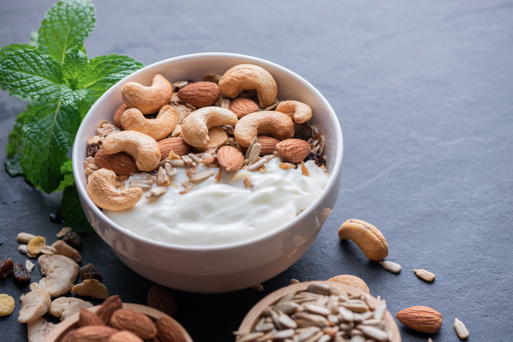 homemade-granola-muesli-bowl-oat-granola-with-yogurt-almond-cashew-nuts-mint-nuts-black-rock-board-healthy-breakfast-copy-space-healthy-breakfast-menu-concept Migdały – wartości odżywcze, kalorie, ile jeść i które wybierać
